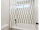 Updated bathroom features a shower with gray and white vertical tile, white tub, and modern fixtures at 4521 W Buffalo St, Chandler, AZ 85226