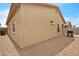Side exterior showcasing a stucco wall, small windows, and a compact gravel area; a grill stands near the corner at 900 W Broadway Ave # 45, Apache Junction, AZ 85120