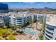 Aerial view shows a blue community pool between white apartment buildings with palm trees and shaded cabanas at 945 E Playa Del Norte Dr # 3002, Tempe, AZ 85288
