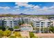 Aerial view showing white apartment buildings with a center courtyard, community pool, and mountain views at 945 E Playa Del Norte Dr # 3002, Tempe, AZ 85288