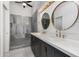 Modern bathroom with a double sink vanity, marble countertops, round mirrors, and a spacious walk-in shower at 102 S Honeysuckle Ln, Gilbert, AZ 85296