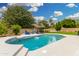Sparkling pool features a tanning ledge, lush landscaping, and an umbrella for shaded poolside relaxation at 102 S Honeysuckle Ln, Gilbert, AZ 85296