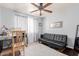 Neutral bedroom featuring a small sofa, window with curtains, and ceiling fan at 10472 W Devonshire Ave, Phoenix, AZ 85037
