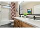 Bathroom with double sinks, wood cabinets, modern fixtures and decorative shower curtain at 11623 W Marguerite Ave, Avondale, AZ 85323