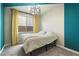 Cozy bedroom with a modern chandelier, bright curtains, and soft, neutral-colored walls at 11623 W Marguerite Ave, Avondale, AZ 85323