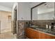 Modern bathroom vanity with dark granite countertop, wood cabinets, large mirror, and open access to walk-in closet at 15217 N 15Th Dr, Phoenix, AZ 85023