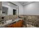 Unique bathroom featuring wood cabinets, stone walls, and a framed mirror at 15217 N 15Th Dr, Phoenix, AZ 85023