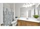 Well-lit bathroom with a shower-tub combo, wood cabinets, and decorative plants at 17132 W Tara Ln, Surprise, AZ 85388