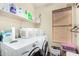 Bright laundry room with white washer and dryer, storage shelves, and a window for natural light, offering a functional space at 19029 N 36Th St, Phoenix, AZ 85050