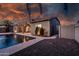 Stunning backyard featuring a sparkling pool, covered patio with furniture, and lush desert landscaping at twilight at 1932 S Arroyo Ln, Gilbert, AZ 85295