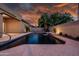 Serene backyard pool with a cascading water feature, surrounded by mature landscaping and ambient lighting for evening swims at 1932 S Arroyo Ln, Gilbert, AZ 85295