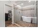 Contemporary bathroom with glass shower, freestanding tub, stone tile, and access to a walk-in closet at 1932 S Arroyo Ln, Gilbert, AZ 85295