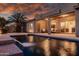 Inviting backyard pool with a tranquil waterfall feature and cozy covered patio at twilight at 1932 S Arroyo Ln, Gilbert, AZ 85295