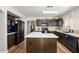 Modern kitchen featuring dark cabinets, a white island, stainless steel appliances and wood-look floors at 22783 W Cantilever St, Buckeye, AZ 85326