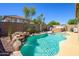 Backyard swimming pool with rock waterfall, hot tub, and pink flamingo floatie on a sunny day at 22783 W Cantilever St, Buckeye, AZ 85326