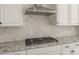 Close-up of a kitchen featuring a stainless steel range hood and gas cooktop over granite countertops at 26160 S 225Th Way, Queen Creek, AZ 85142