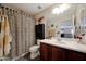 Well-lit bathroom with a single sink vanity, a decorative shower curtain, and a large mirror at 30185 W Flower St, Buckeye, AZ 85396