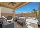 Relaxing covered patio with comfortable seating and ceiling fan, offering views of the backyard and pool at 30185 W Flower St, Buckeye, AZ 85396