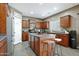 Well-lit kitchen showcasing an island with seating, brown cabinets and stainless steel appliances at 30185 W Flower St, Buckeye, AZ 85396