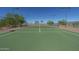 Another shot of the well-maintained tennis court with green surface and surrounding fence and lighting at 30185 W Flower St, Buckeye, AZ 85396