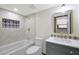 Bright bathroom featuring a tub with tile surround, blue vanity, and decorative mirror at 3441 N 31St St # 118, Phoenix, AZ 85016