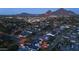 Aerial night view of homes featuring a backyard pool, spa, fire pit, landscaped yard, and mountain views at 3653 E Highland Ave, Phoenix, AZ 85018