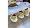 Three delectable deviled eggs topped with beets on a wooden serving board, alongside chips and sauce at 3653 E Highland Ave, Phoenix, AZ 85018