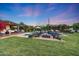 Outdoor fire pit surrounded by Adirondack chairs, with a pool and manicured landscaping in the background at 3653 E Highland Ave, Phoenix, AZ 85018