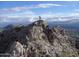 Hikers on a rocky mountain peak with scenic views of the city and expansive sky at 3653 E Highland Ave, Phoenix, AZ 85018