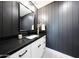 Stylish powder room with dark vertical plank walls, a white vanity, and a modern black faucet at 3653 E Highland Ave, Phoenix, AZ 85018