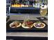 Delicious variety of tacos on a black plate with a drink in the background, perfect for a tasty meal at 3653 E Highland Ave, Phoenix, AZ 85018