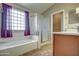 Bright bathroom featuring a soaking tub, glass-enclosed shower and wood vanity at 40437 W Robbins Dr, Maricopa, AZ 85138