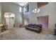 A bright living room featuring soaring ceilings and large windows with wood blinds and carpet flooring at 40437 W Robbins Dr, Maricopa, AZ 85138