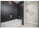 This bathroom features a soaking tub with a shower and textured black tile at 4506 W Golden Ln, Glendale, AZ 85302