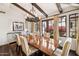 Elegant dining area with a dark wood table, chandelier, exposed beams, and natural light from the windows at 4949 E Lincoln Dr # 11, Paradise Valley, AZ 85253