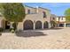 Elegant home exterior featuring multiple garage spaces, a second-story balcony, and mature trees at 4949 E Lincoln Dr # 11, Paradise Valley, AZ 85253