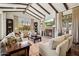 Bright living room featuring beamed ceilings, a stone fireplace, large windows with natural light, and neutral-toned furniture at 4949 E Lincoln Dr # 11, Paradise Valley, AZ 85253