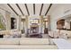 A living room with beamed ceilings, comfortable seating, a stone fireplace, and views of the open kitchen at 4949 E Lincoln Dr # 11, Paradise Valley, AZ 85253
