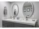 Bright bathroom featuring dual sinks with gray cabinets and oval-shaped decorative mirrors at 519 E El Camino Dr, Phoenix, AZ 85020
