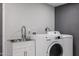 Functional laundry area equipped with a sink, storage cabinets, and a modern washer and dryer at 519 E El Camino Dr, Phoenix, AZ 85020