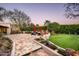 An outdoor patio leads to a verdant lawn and comfortable seating areas under mature trees at 6019 N 62Nd Pl, Paradise Valley, AZ 85253