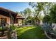 Lush backyard featuring artificial turf, a tiled patio, and mature trees and cacti at 6019 N 62Nd Pl, Paradise Valley, AZ 85253