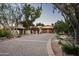Long circular driveway leading to a two-car garage with flowering vines and trees at 6019 N 62Nd Pl, Paradise Valley, AZ 85253