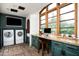 Bright laundry room with front load washer/dryer, desk area, and a view of the exterior at 6019 N 62Nd Pl, Paradise Valley, AZ 85253