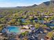 Community aerial view with a pool, clubhouse, parking, tennis courts, and houses nestled in desert landscape with mountains at 6591 E Amber Sun Dr, Scottsdale, AZ 85266