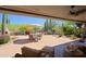 Covered patio with seating and a landscaped backyard with desert plants and waterfall feature at 6591 E Amber Sun Dr, Scottsdale, AZ 85266