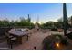 Spacious backyard featuring an outdoor dining area, built-in BBQ, and fireplace on a stone paver patio at 6591 E Amber Sun Dr, Scottsdale, AZ 85266
