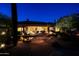 Desert backyard featuring a pool, patio, and lush landscaping illuminated at night at 6591 E Amber Sun Dr, Scottsdale, AZ 85266