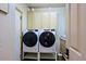 Bright laundry room with stacked washer and dryer units and storage cabinets at 6591 E Amber Sun Dr, Scottsdale, AZ 85266