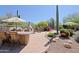 Inviting outdoor patio featuring a built-in grill, fireplace, desert landscaping and a charming dining area under an umbrella at 6591 E Amber Sun Dr, Scottsdale, AZ 85266